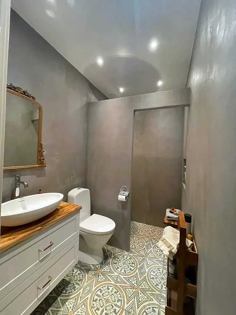 Badrum med väggar i microcement och mönstrat klinker