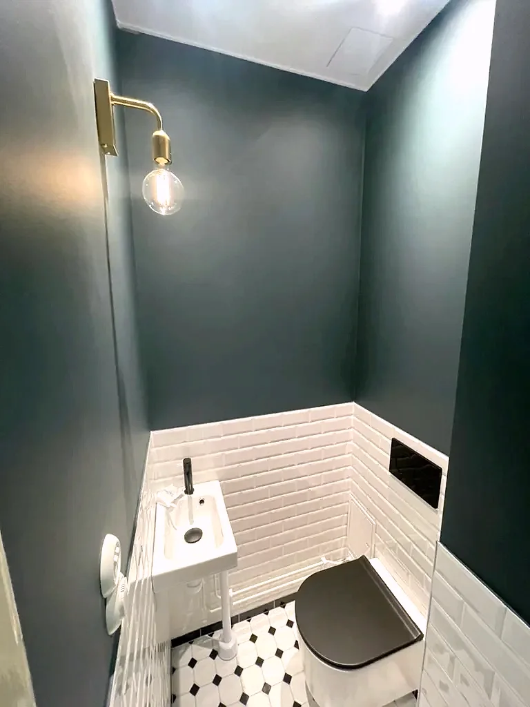 WC med mörkgröna väggar och vitt fasat kakel