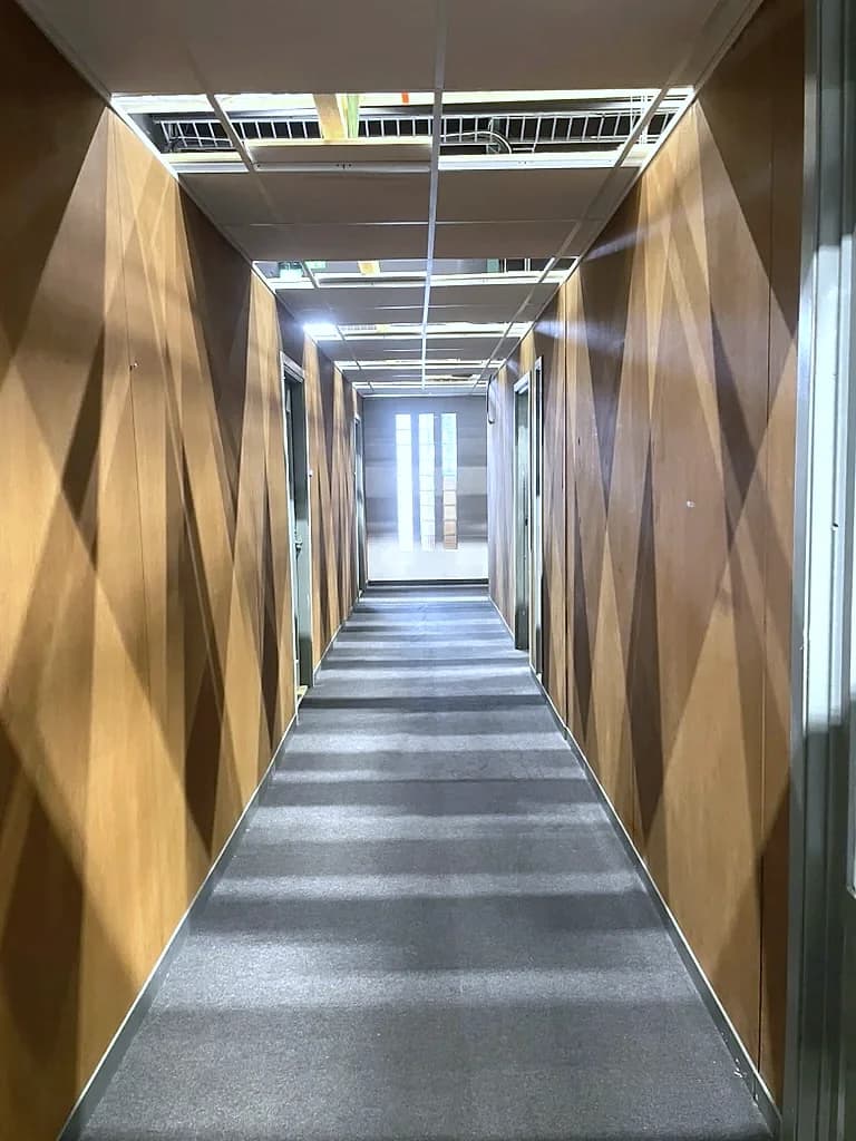 Träklädd korridor i inspelningsmiljön, med öppningar i kulisstaket