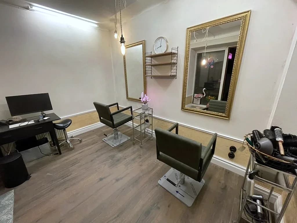 Arbetsstationer med guldfärgade spegelramar och gröna salongsstolar